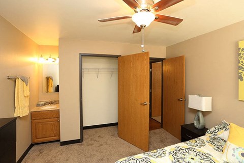 A bedroom with a bed, dresser, mirror, and a ceiling fan.