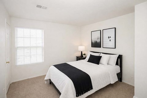 A bedroom with a bed, nightstand, and two pictures on the wall.