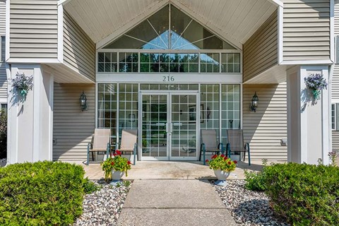 the front entrance of a building with a patio and chairs