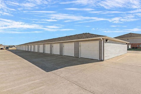 A long building with a grey roof and white garage doors.