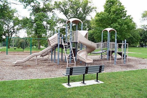 a playground with slides and a bench in a park