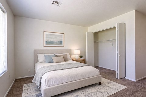 A bedroom with a bed, a lamp, and a painting on the wall.