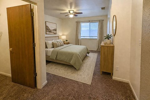 A bedroom with a bed, nightstand, and a ceiling fan.