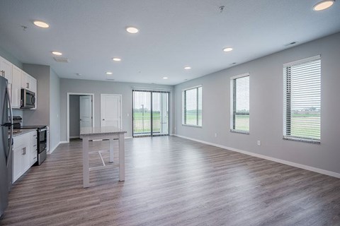 A spacious kitchen with wooden floors and white cabinets.