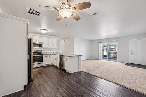 A spacious kitchen with white cabinets and a ceiling fan.