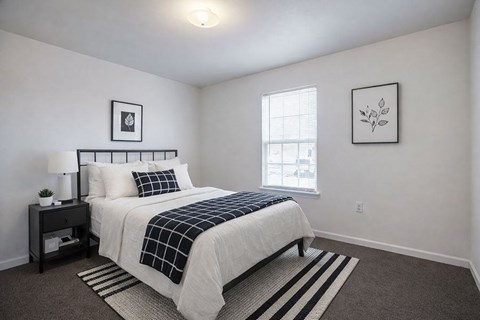 A bedroom with a bed, nightstand, and two pictures on the wall.