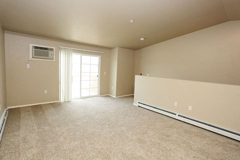 A spacious room with a window and carpeted floor.