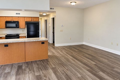 A kitchen with wooden cabinets and a black fridge.