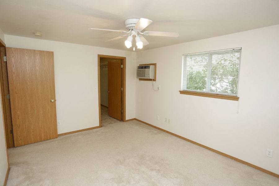 an empty living room with a ceiling fan and a window