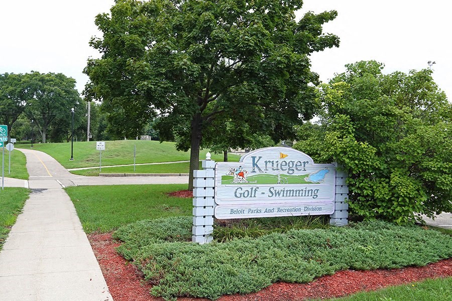a sign for a golf course with a tree