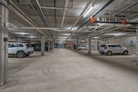 A parking garage with concrete floors and multiple cars parked.