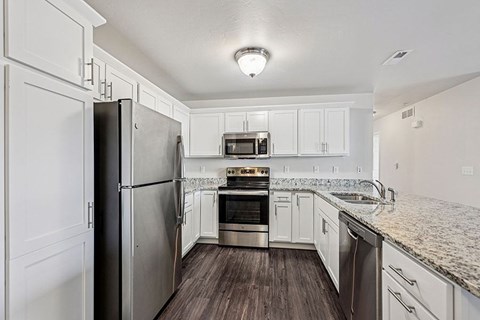 A kitchen with a refrigerator, oven, microwave, and sink.