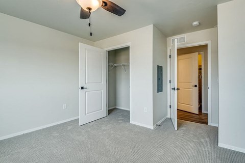 an empty bedroom with a closet and a ceiling fan