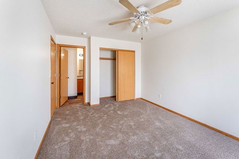 A room with a ceiling fan and carpeted floor.