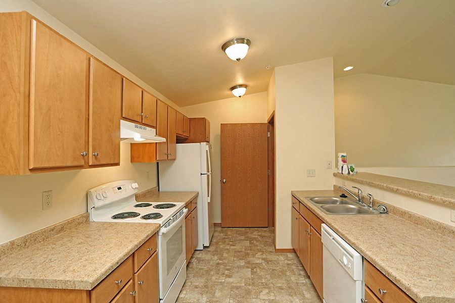 A kitchen with a white stove top oven and a white dishwasher.