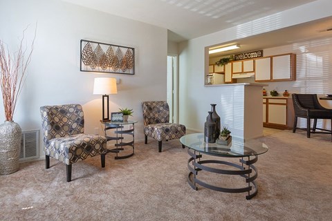 A living room with two chairs, a table, and a mirror.