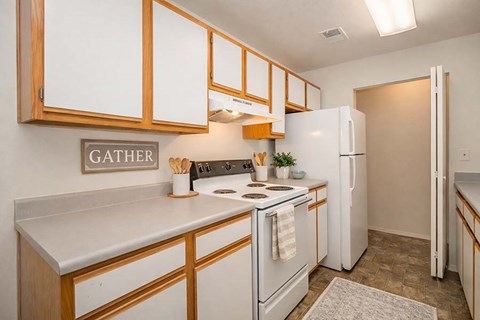 A kitchen with white appliances and wooden cabinets.