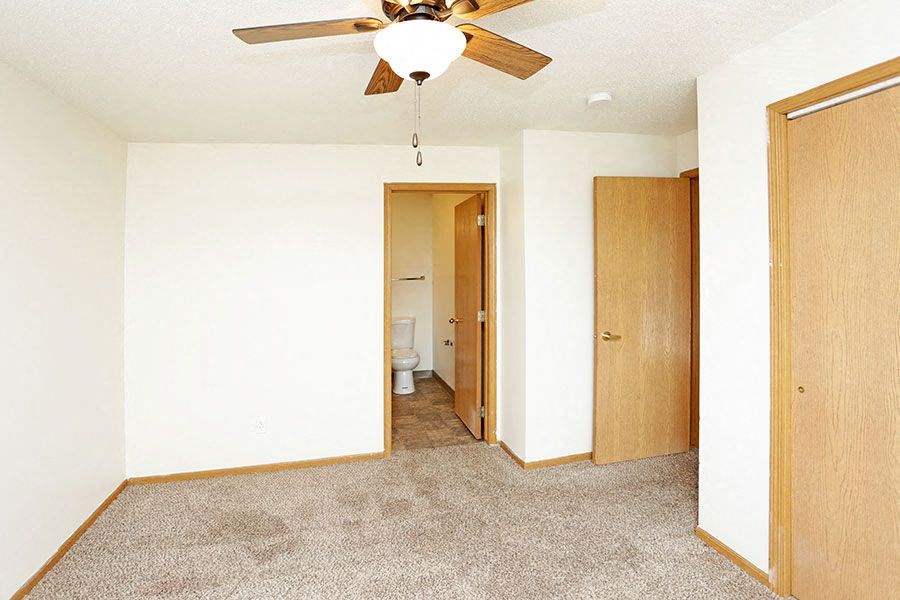 an empty room with a ceiling fan and a door to a bathroom