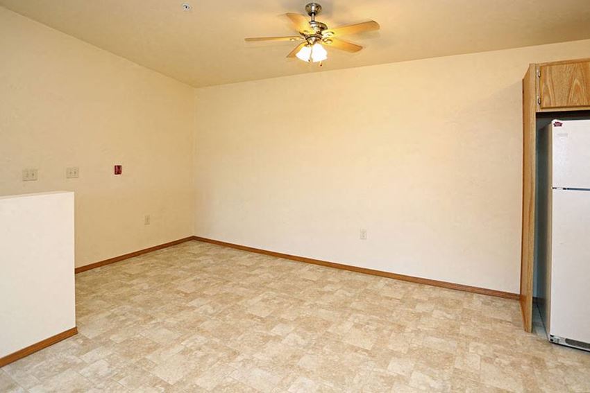 an empty room with a refrigerator and a ceiling fan
