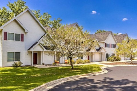 a row of white houses with a tree in the yard