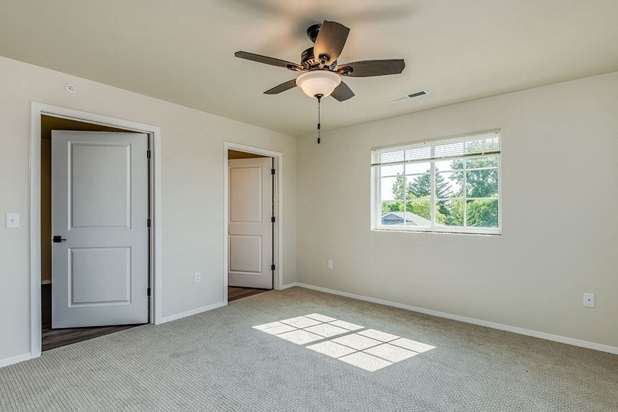 an empty living room with a ceiling fan