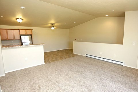 an empty room with a kitchen and a carpet floor