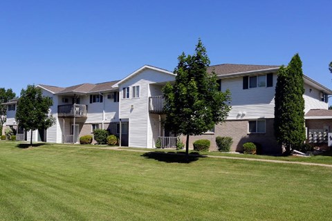 an apartment building with a green lawn and trees
