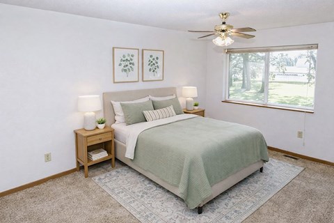 A bedroom with a bed, nightstand, and two framed pictures on the wall.