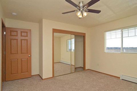 an empty bedroom with a ceiling fan and a mirror