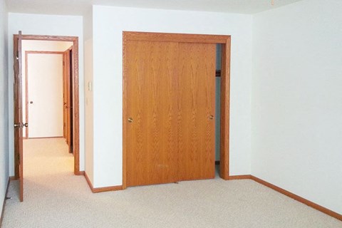 an empty room with a wooden door and a hallway