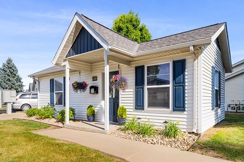 A house with a grey roof and a white wall with a window and a door.