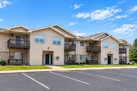 A row of apartment buildings with a parking lot in front.