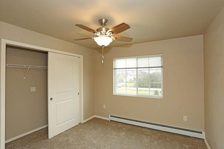 an empty bedroom with a ceiling fan and a closet
