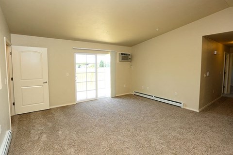 an empty living room with a door and a window