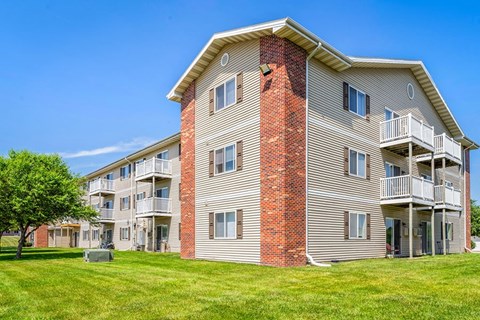 A large apartment building with a red brick chimney and a balcony on the second floor.