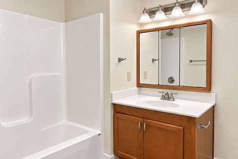 A white bathroom with a wooden cabinet and a white sink.