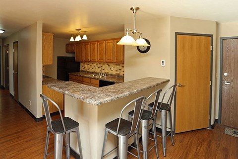 A kitchen with a granite counter top and bar stools.