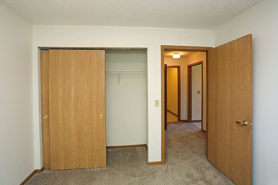 an empty room with a closet and a door to a bedroom