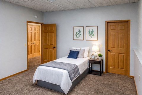 A bedroom with a bed, nightstand, and two doors.