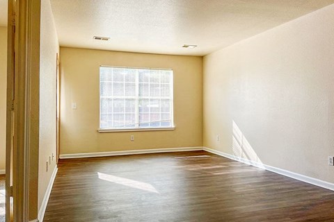 an empty room with a window and a hard wood floor