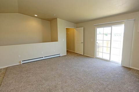 an empty living room with a door to a balcony