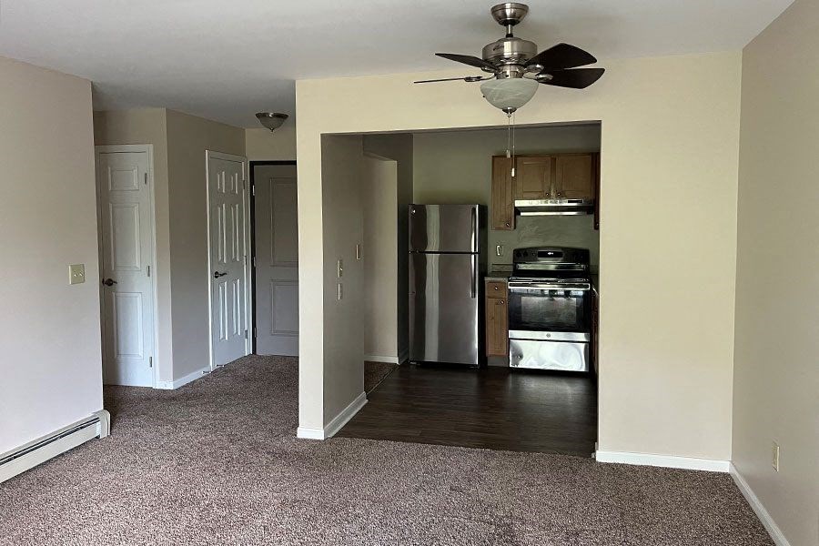 a empty room with a ceiling fan and a refrigerator