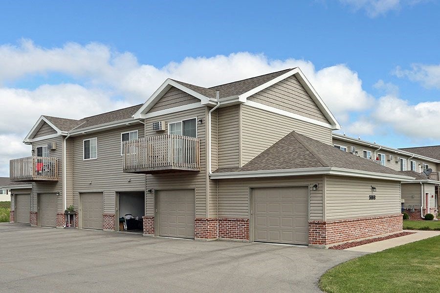 a beige house with a balcony and garage doors