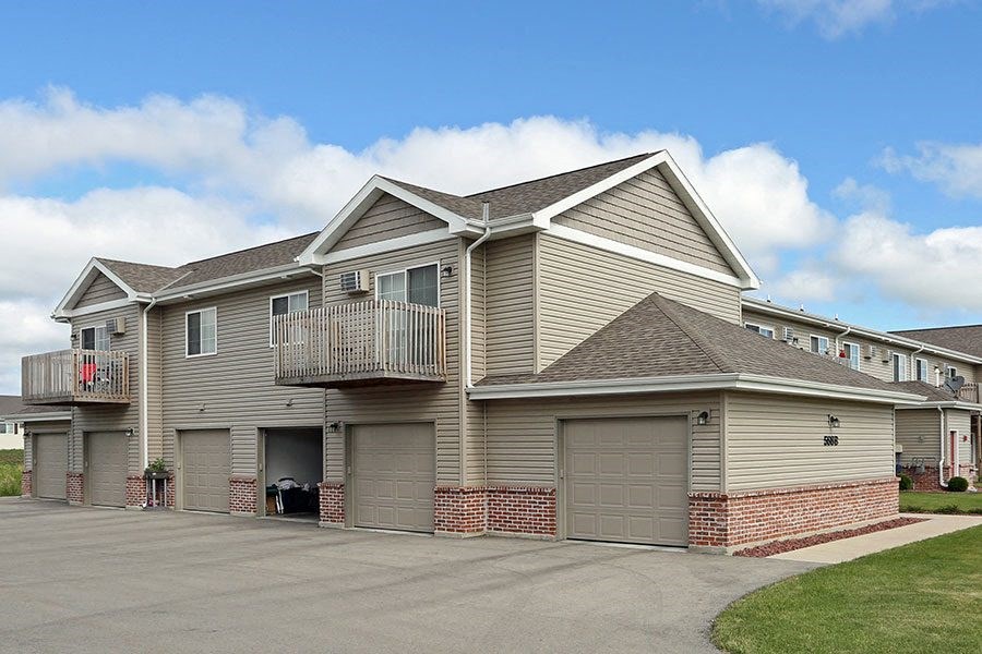 a beige house with a balcony and garage doors