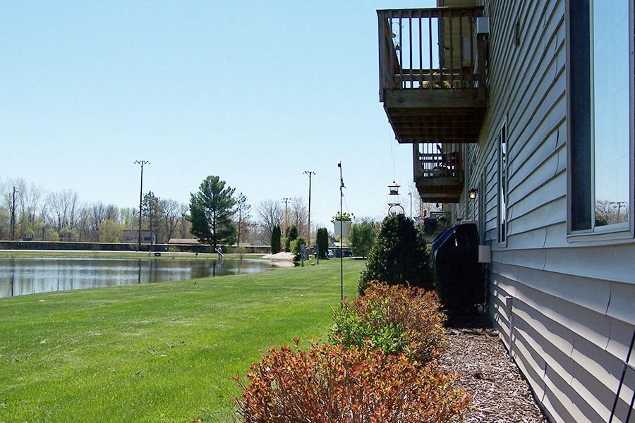 the side of a house with a yard and a lake