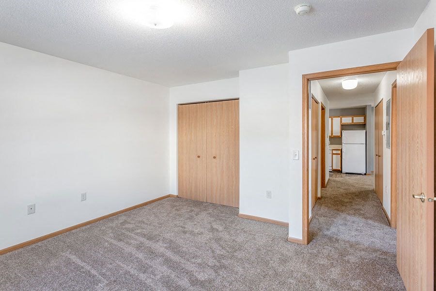 an empty living room with a hallway to a kitchen