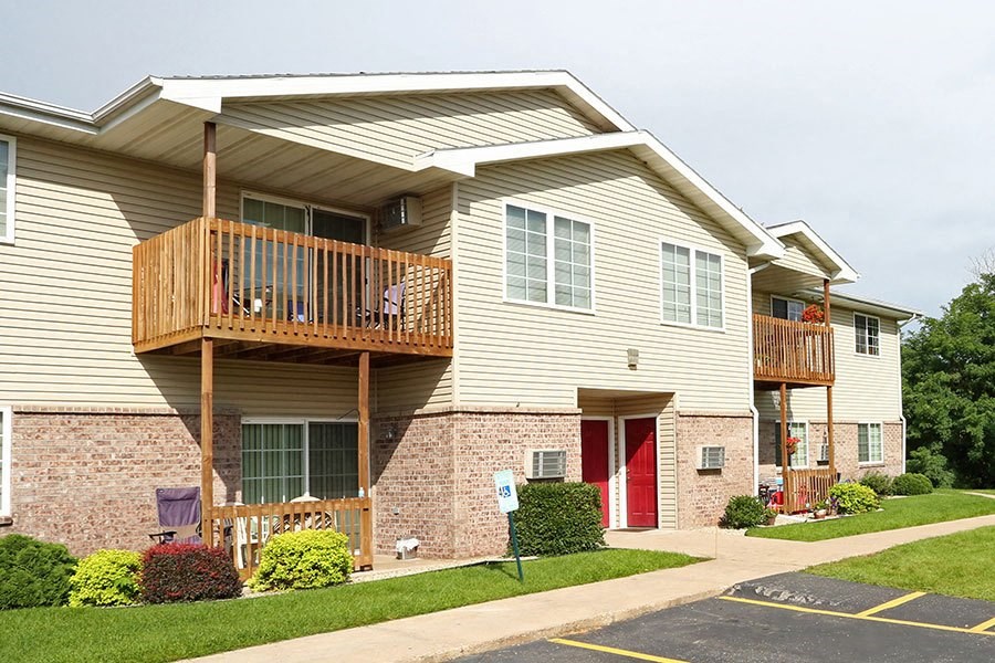 a yellow house with a balcony and a red door