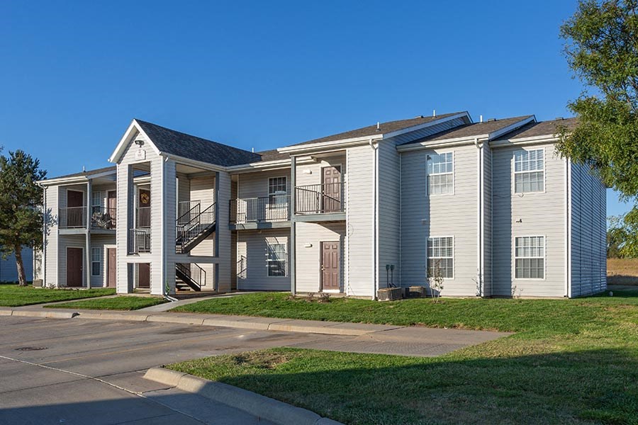 a row of apartment buildings with stairs and grass