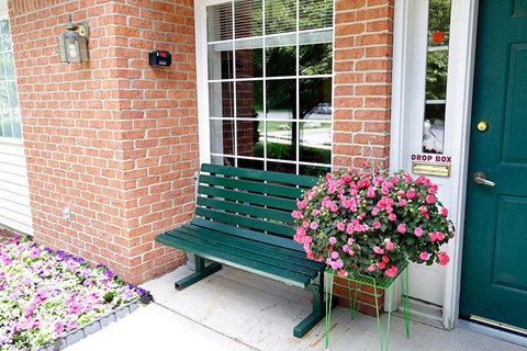 a green bench sitting in front of a brick building