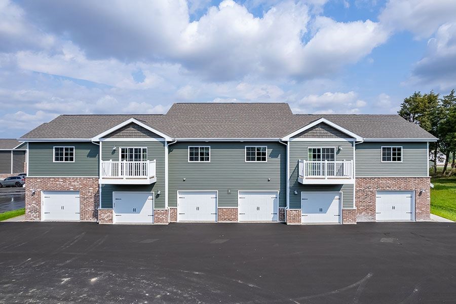 A large two-story house with a grey roof and a balcony on the second floor.